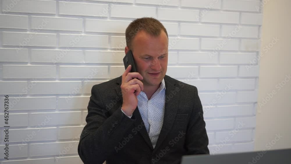 Closeup smiling man talking mobile phone in office. Close up of cheerful businessman having phone call at workplace in slow motion. Closeup smiling man talking mobile phone in office. Close up of cheerful businessman having phone call at workplace in slow motion.