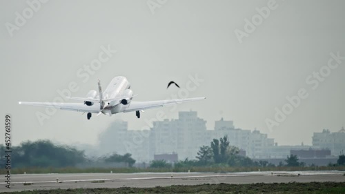 A small private plane takes off in urban scenery. The wheels of a light aircraft detach from the runway of the airport.