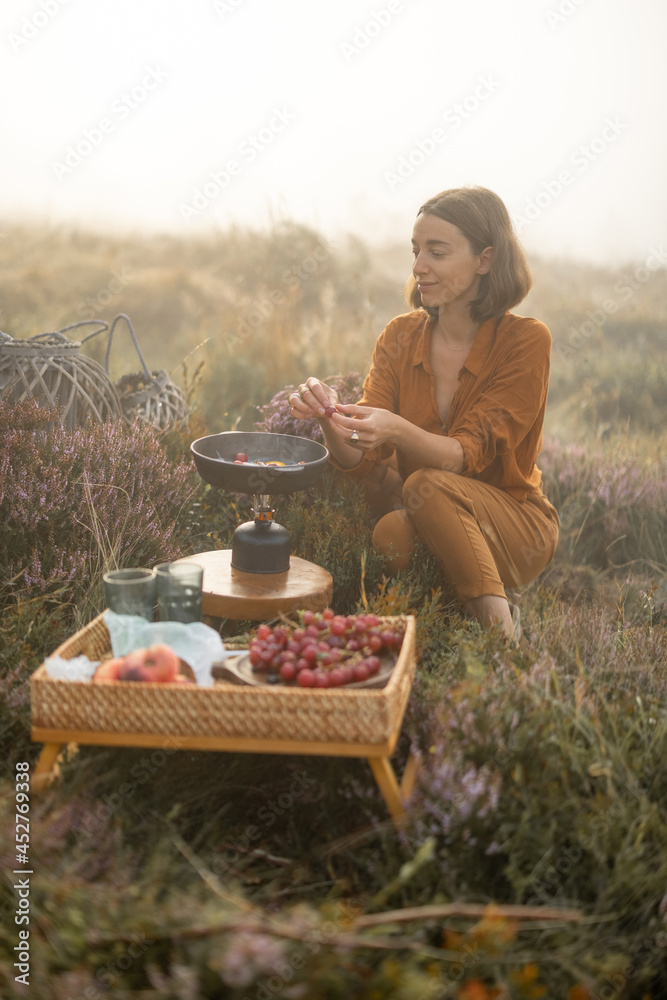Woman traveler has a beautiful berakfast time with eggs and fruits while traveling in mountains on foggy weather - obrazy, fototapety, plakaty 