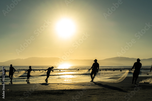 Pescadores puxam rede de pesca ao nascer do sol na praia - Paisagem natural