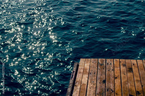 Wooden pier at the blue water of the sea in sunlight © shapovalphoto