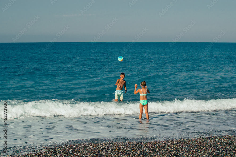 two children playing ball on the beach