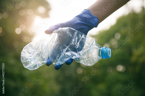 Woman hand picking up trash plastic bottle, ecology concept