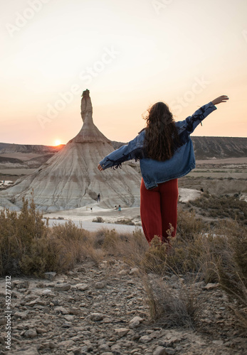 Woman looking at a sand formation in the Bardenas Reales desert at sunset