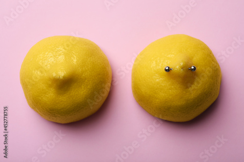 Yellow lemon halves with piercing on pink background, flat lay