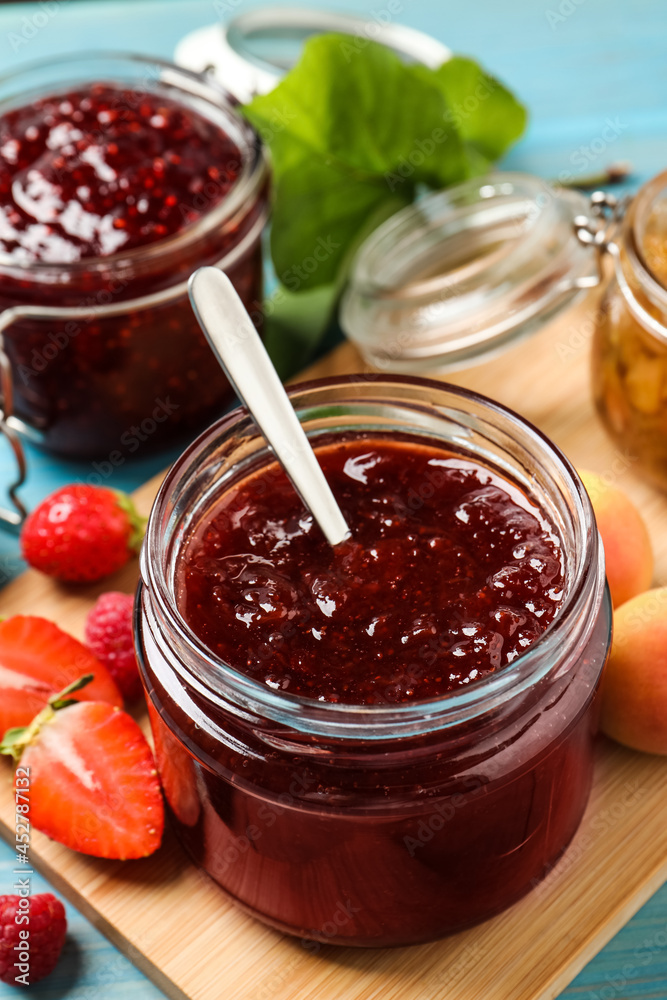 Jars with different jams and fresh fruits on light blue wooden table, closeup Jars with different jams and fresh fruits on light blue wooden table, closeup