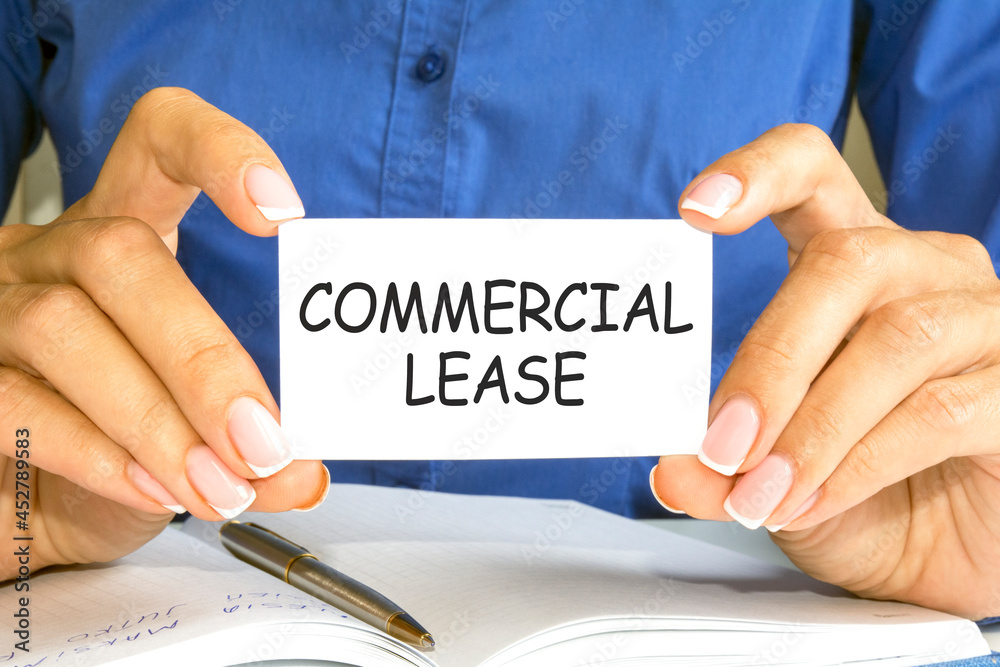 the woman's hands hold a business card with text commercial lease, business and finance concept the woman's hands hold a business card with text commercial lease, business and finance concept