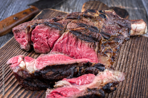 Traditional barbecue wagyu tomahawk beef steak sliced and served as close-up on a rustic wooden board