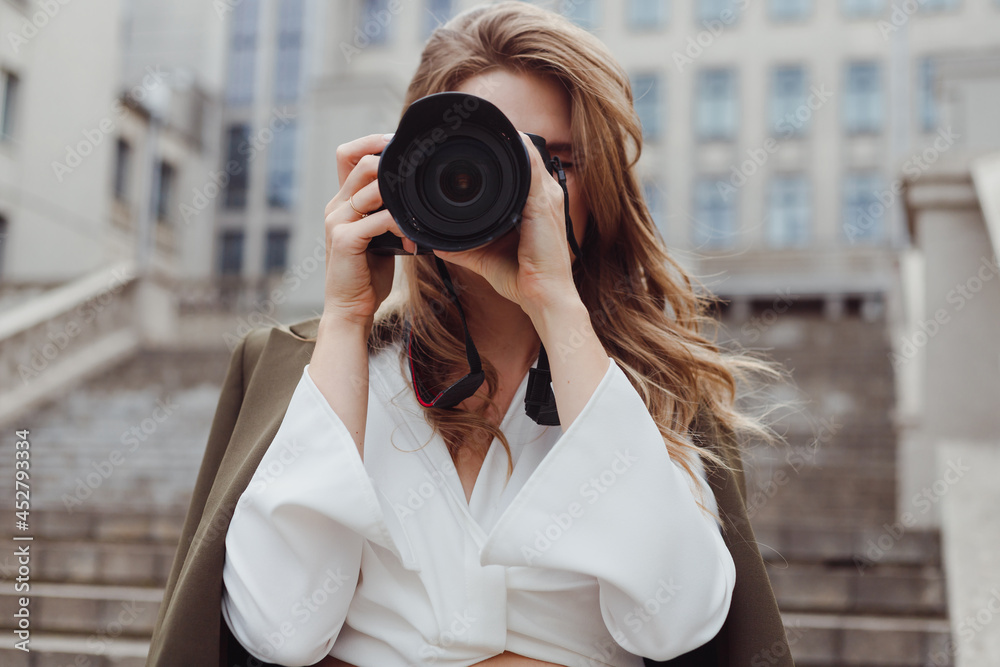 Portrait of woman photographer covering her face with camera outdoors