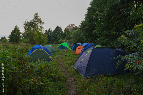 Tourist tents on the background of a summer field at sunrise. Adventure traveling lifestyle. Concept wanderlust. Active weekend vacations wild nature outdoor.