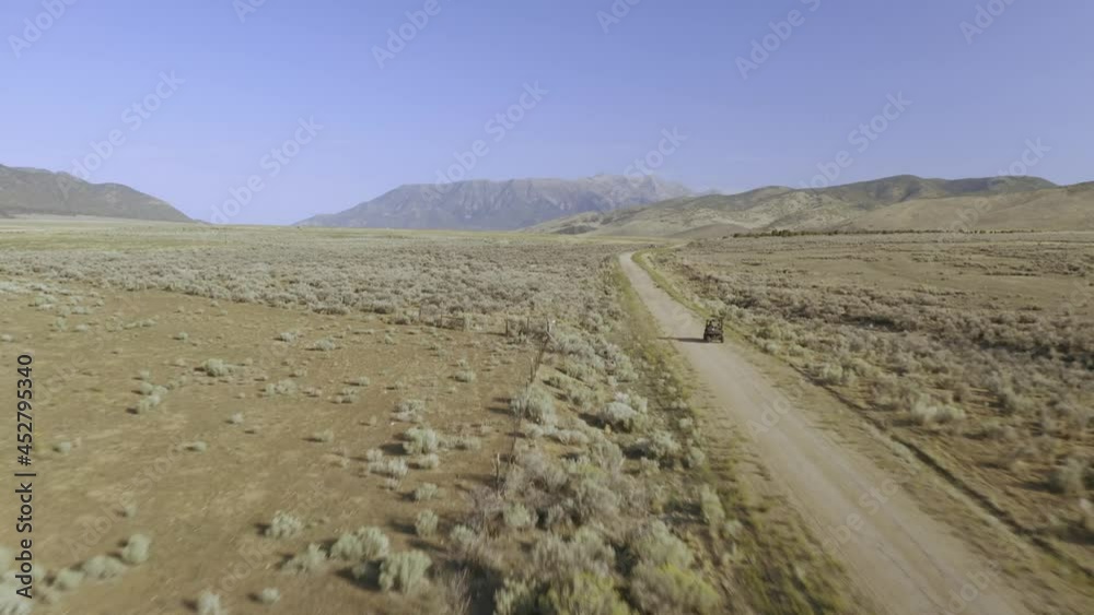 Aerial-Following a side by side UTV off-road vehicle on dirt road toward distant mountain on a hot dry summer day Aerial-Following a side by side UTV off-road vehicle on dirt road toward distant mountain on a hot dry summer day
