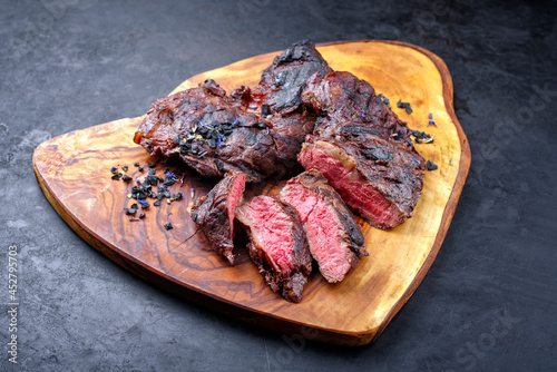 Traditional barbecue wagyu spider beef steak with black salt and spices served as close-up on a rustic wooden board with copy space photo