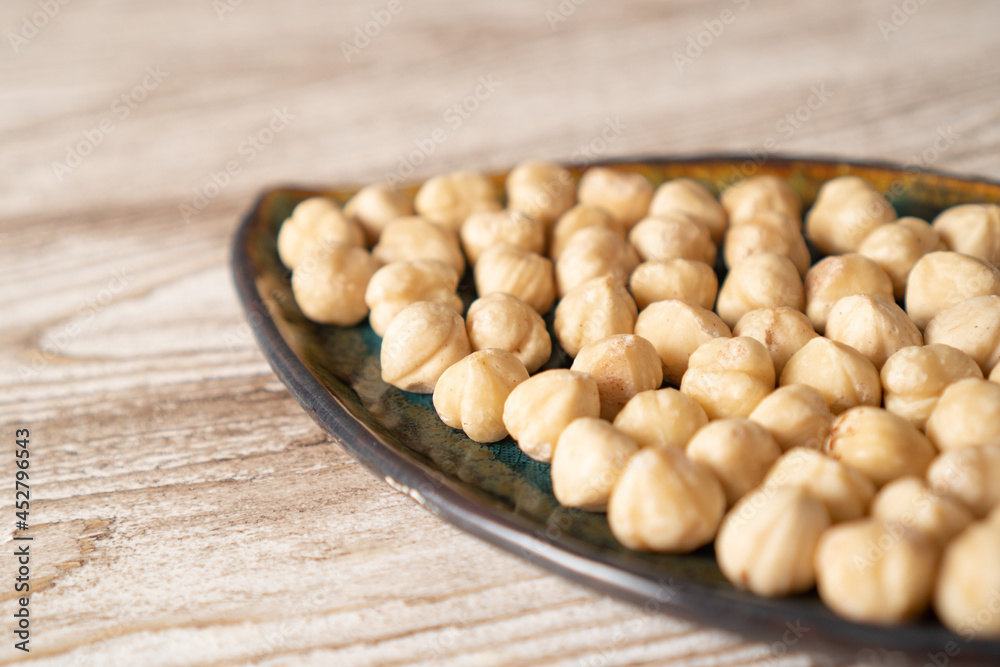 Hazelnuts in bowl. Peeled roasted hazelnut kernels on a plate on wooden table Hazelnuts in bowl. Peeled roasted hazelnut kernels on a plate on wooden table