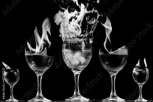 Taças de cristal com bebida e pedras de gelo dentro explodindo em chamas. 