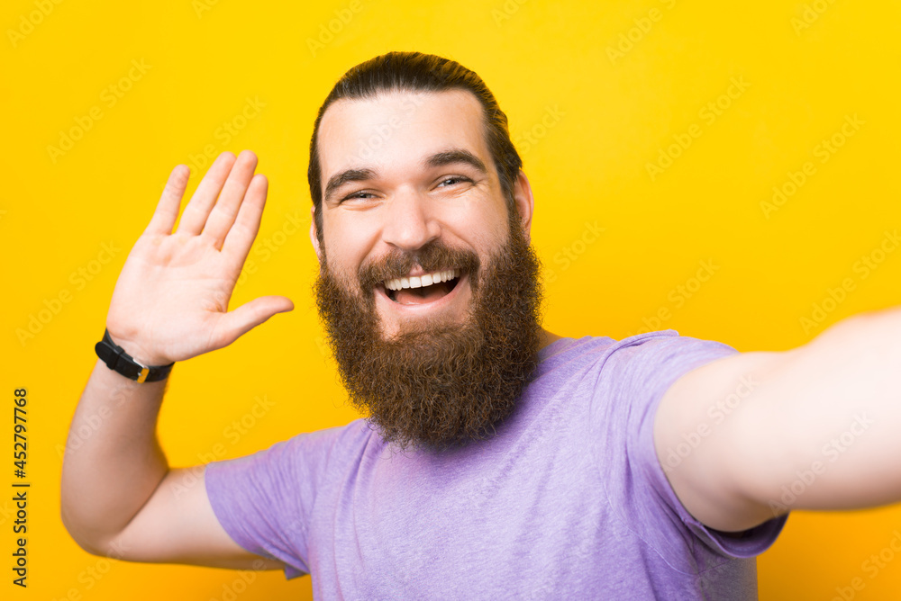 Friendly bearded man is saying hi while taking a selfie. Friendly bearded man is saying hi while taking a selfie.