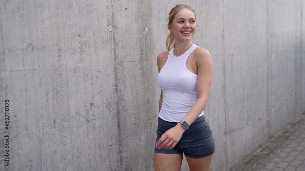 Cheerful sportswoman walking after workout on street Cheerful sportswoman walking after workout on street