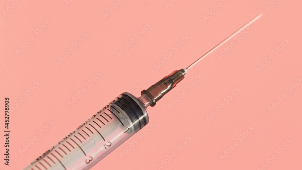 Close-up of a doctor's hands preparing a vaccine for injection on a red background Close-up of a doctor's hands preparing a vaccine for injection on a red background