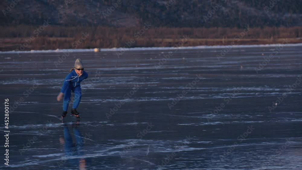 The girl train on ice speed skating. The child skates in the winter in blue sportswear suit, sport glasses. Children speed skating sport. Outdoor slow motion. Snow capped mountains, beautiful ice. The girl train on ice speed skating. The child skates in the winter in blue sportswear suit, sport glasses. Children speed skating sport. Outdoor slow motion. Snow capped mountains, beautiful ice.