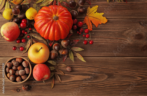 colorful leaves, pumpkin, nuts, apples and mushrooms on wooden background