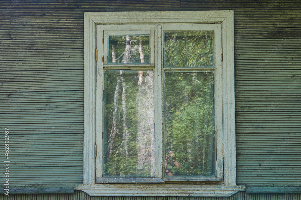 Fototapeta premium Old white wooden window in an old wooden rustic green house with green plank walls 