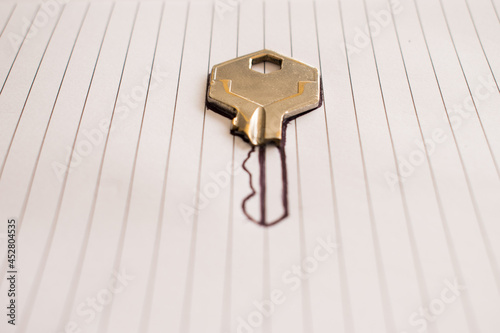Metal broken key  on a dasign of a key on a white background with vertical lines photo