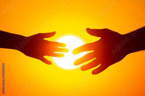 two hands reach out to each other against the background of the sun. communication and romance in human relationships