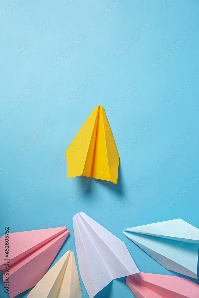 Yellow paper plane leading others on turquoise background, flat lay. Diversity concept