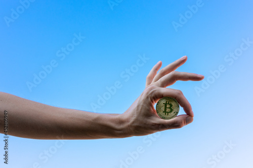 Mano de mujer mostrando un bitcoin con gesto de Ok