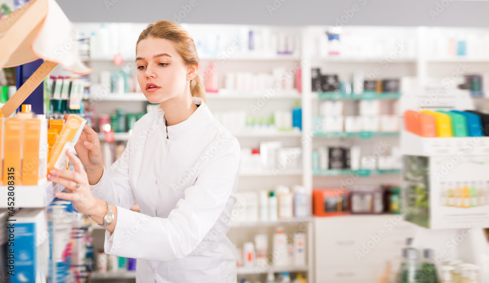 Nice pharmacist is browsing rows of body care products in pharmacy