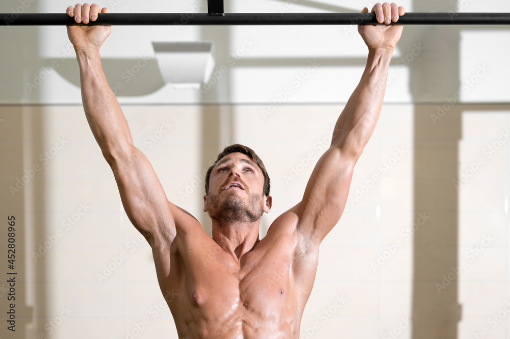 Athlete doing pull-ups at the gym. Handsome man doing functional training. High quality photo. Athlete doing pull-ups at the gym. Handsome man doing functional training. High quality photo.