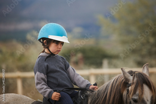 5-year-old girl riding on a horse, in a hipico club. infalltil sport concept