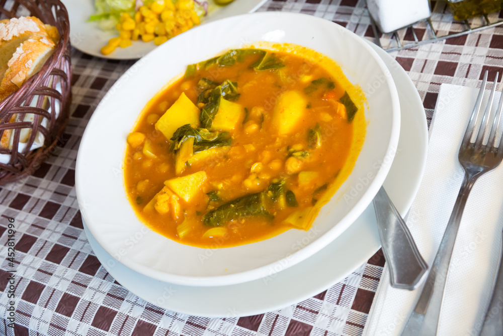 Dish of Spanish cuisine. Traditional thick chickpea soup with greens..