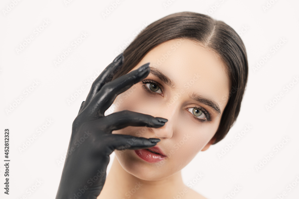 Light-skinned girl with a black hand from the paint. Looking straight into the camera is covered by the hand. Light-skinned girl with a black hand from the paint. Looking straight into the camera is covered by the hand.