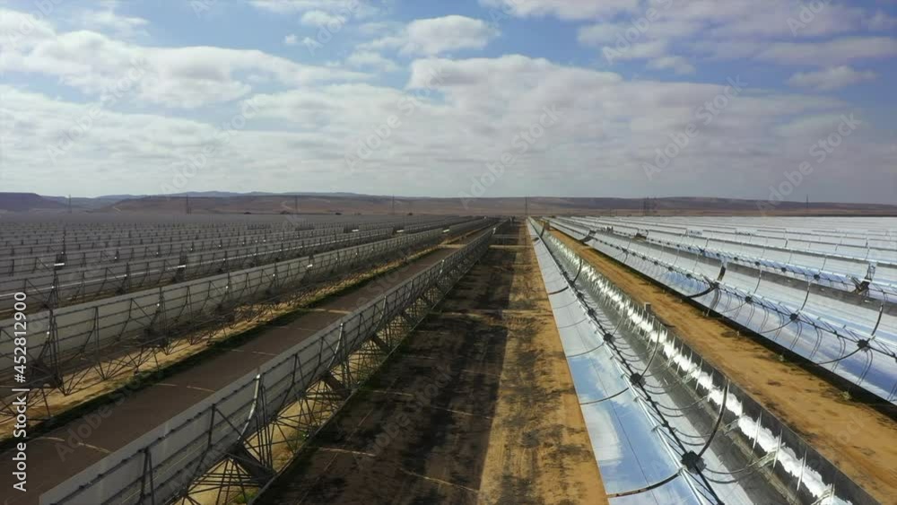 Aerial Backward Shot Of Silver Solar Panels Over Landscape On Sunny Day Against Cloudy Sky - Negev, Israel Aerial Backward Shot Of Silver Solar Panels Over Landscape On Sunny Day Against Cloudy Sky - Negev, Israel