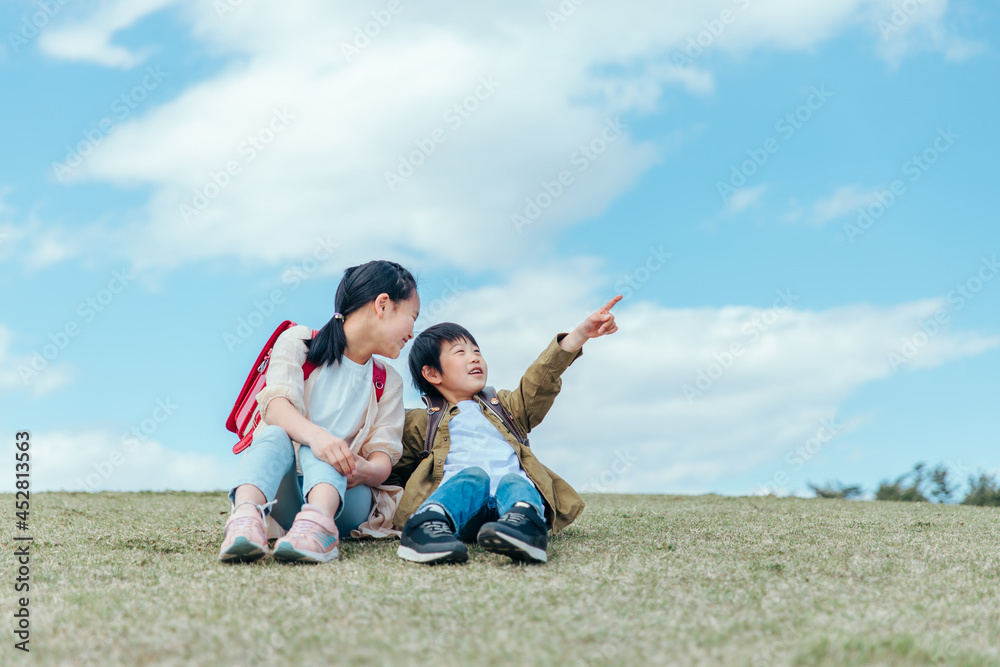 芝生に座る小学生(指差す)
芝生に座る小学生(指差す)