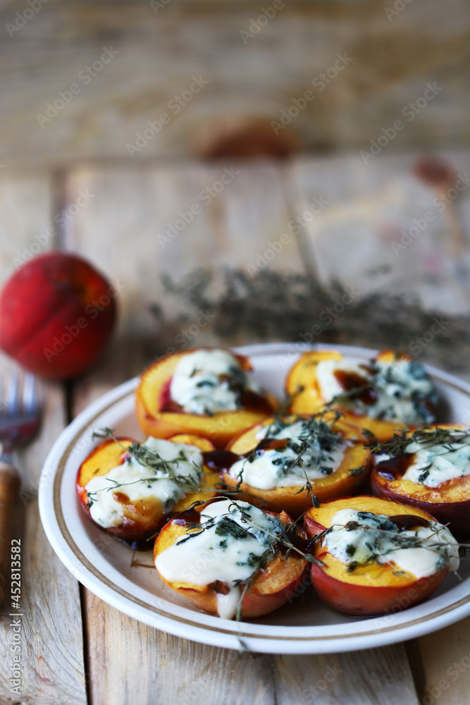 Peaches halves with blue cheese and thyme on a plate.