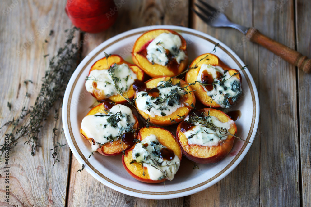 Peaches halves with blue cheese and thyme on a plate. Peaches halves with blue cheese and thyme on a plate.