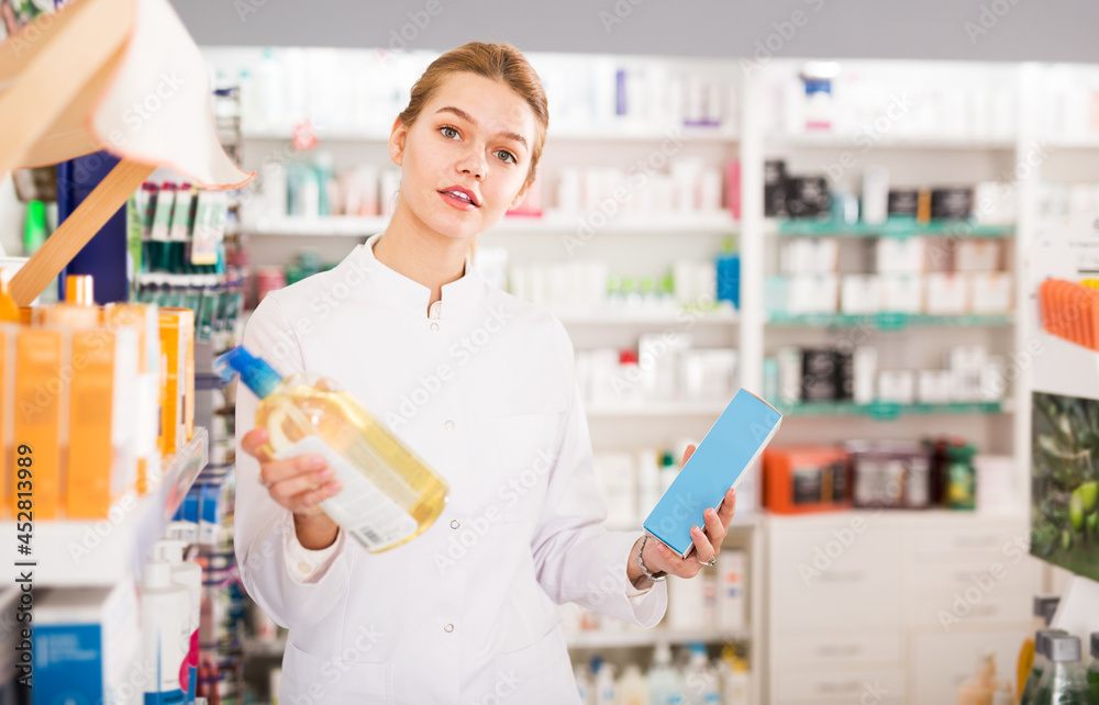 Young friendly female pharmacist offering reliable medicine in pharmacy