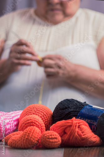 elderly woman 60 year old latin grandmother knitting happy and comfortable inside her home