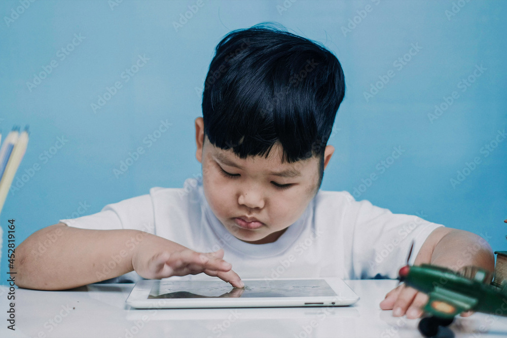 Asian little boy touching and watching on tablet computer at home, Close up. Asian little boy touching and watching on tablet computer at home, Close up.