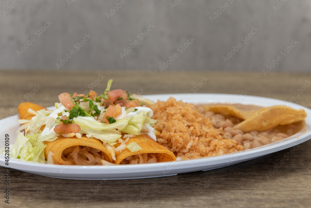 Hearty plate of enchiladas covered sour cream, pico de gallo, and