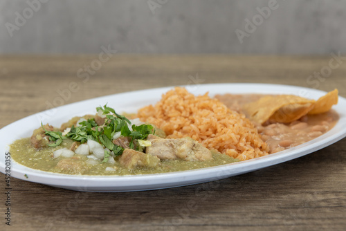 Hearty plate of chili verde smothered in green sauce served with rice and refried beans