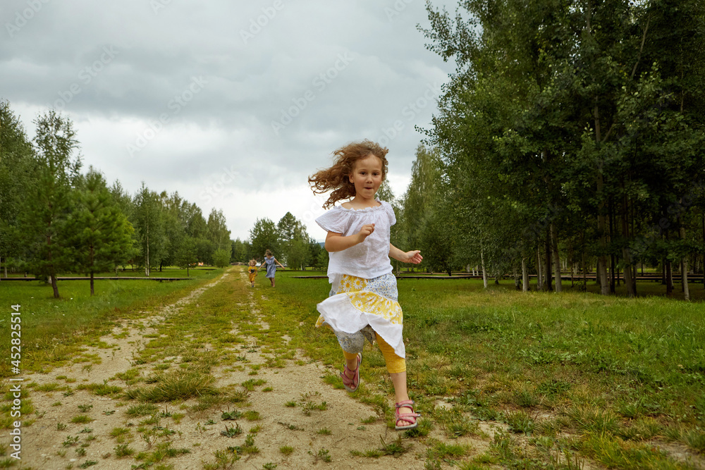 Funny girl in skirt and blouse running on road towards camera against cloudy sky while spending weekend day near grove in nature Funny girl in skirt and blouse running on road towards camera against cloudy sky while spending weekend day near grove in nature