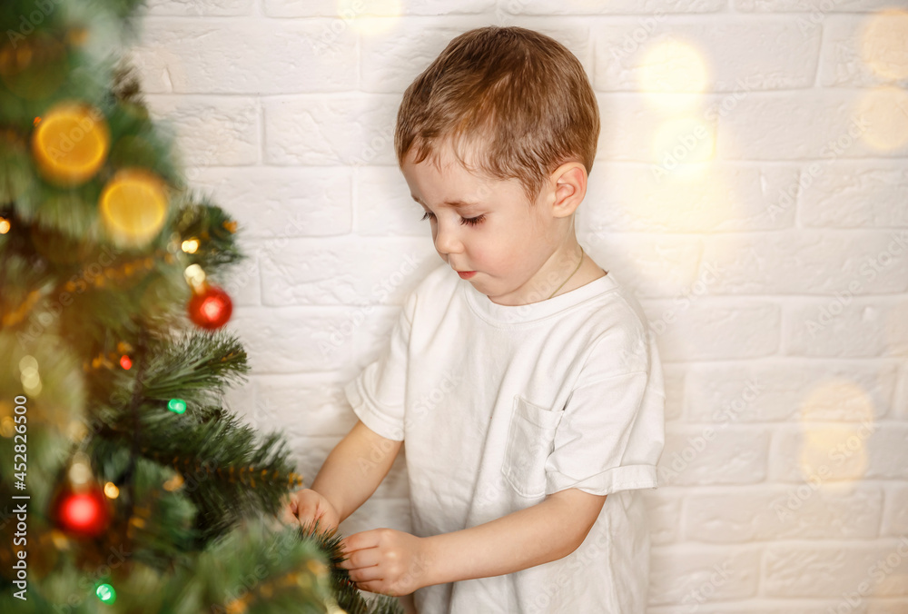Kid decorate Christmas tree at home. Child on Xmas eve. Family decorating Christmas tree with ornaments. Winter holidays. Helping mum with the tree. Christmas preparations. Merry Xmas, Happy Holidays Kid decorate Christmas tree at home. Child on Xmas eve. Family decorating Christmas tree with ornaments. Winter holidays. Helping mum with the tree. Christmas preparations. Merry Xmas, Happy Holidays