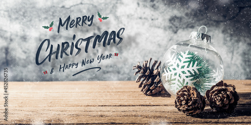 Merry Christmas and happy new year sign with Christmas tree  bauble and pine cone on wood table with concrete wall for celebrate holiday greeting card background