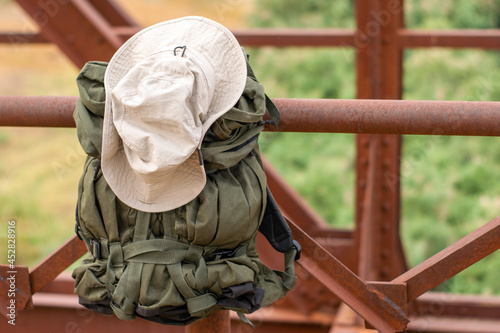 a tourist's backpack and hat hang on the railing of the old iron bridge over the river concept of travel tourism