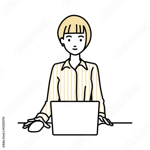 デスクで座ってPCを使っているブラウスの女性