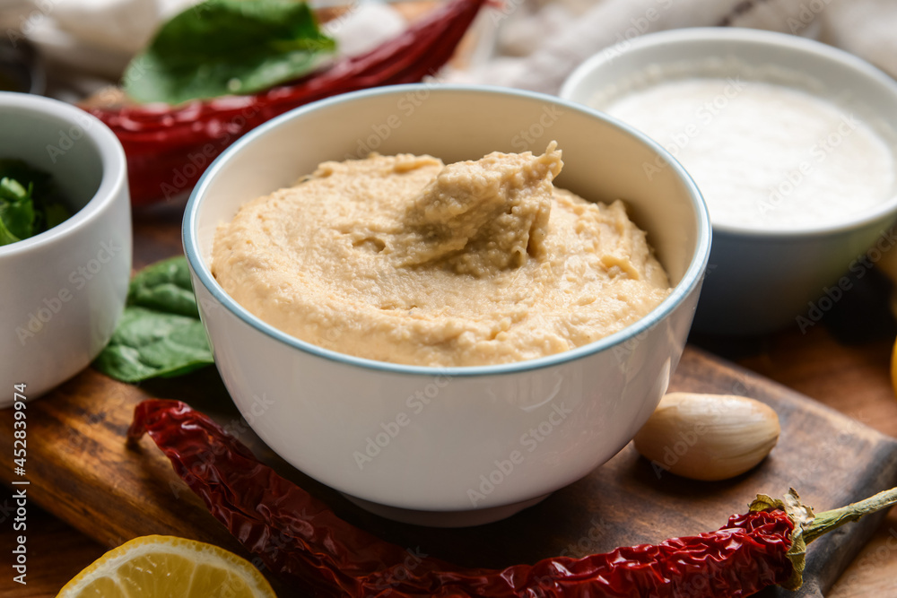 Bowl with tasty hummus and ingredients on table, closeup Bowl with tasty hummus and ingredients on table, closeup