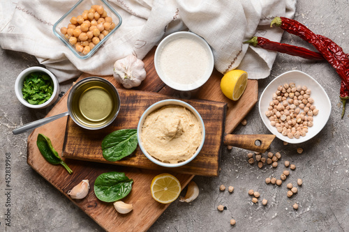 Composition with tasty hummus and ingredients on grunge background