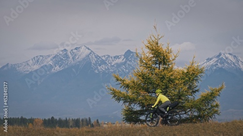 The woman travel on mixed terrain cycle touring with bikepacking. The traveler journey with bicycle bags. Sport tourism bikepacking, bike, sportswear in green black colors. Mountain snow capped. photo